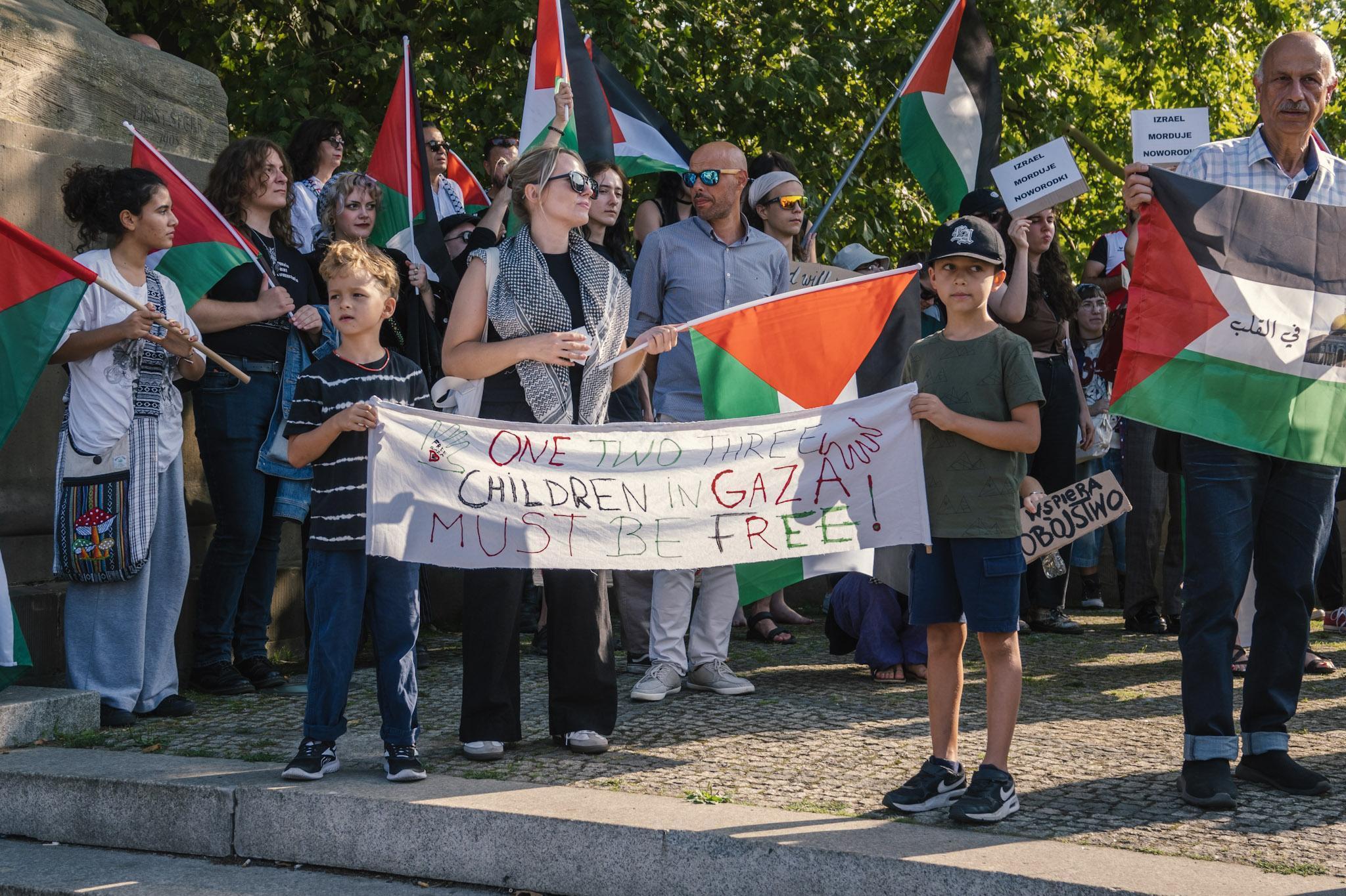 Children holding a banner: “One two three / children in Gaza / must be free”