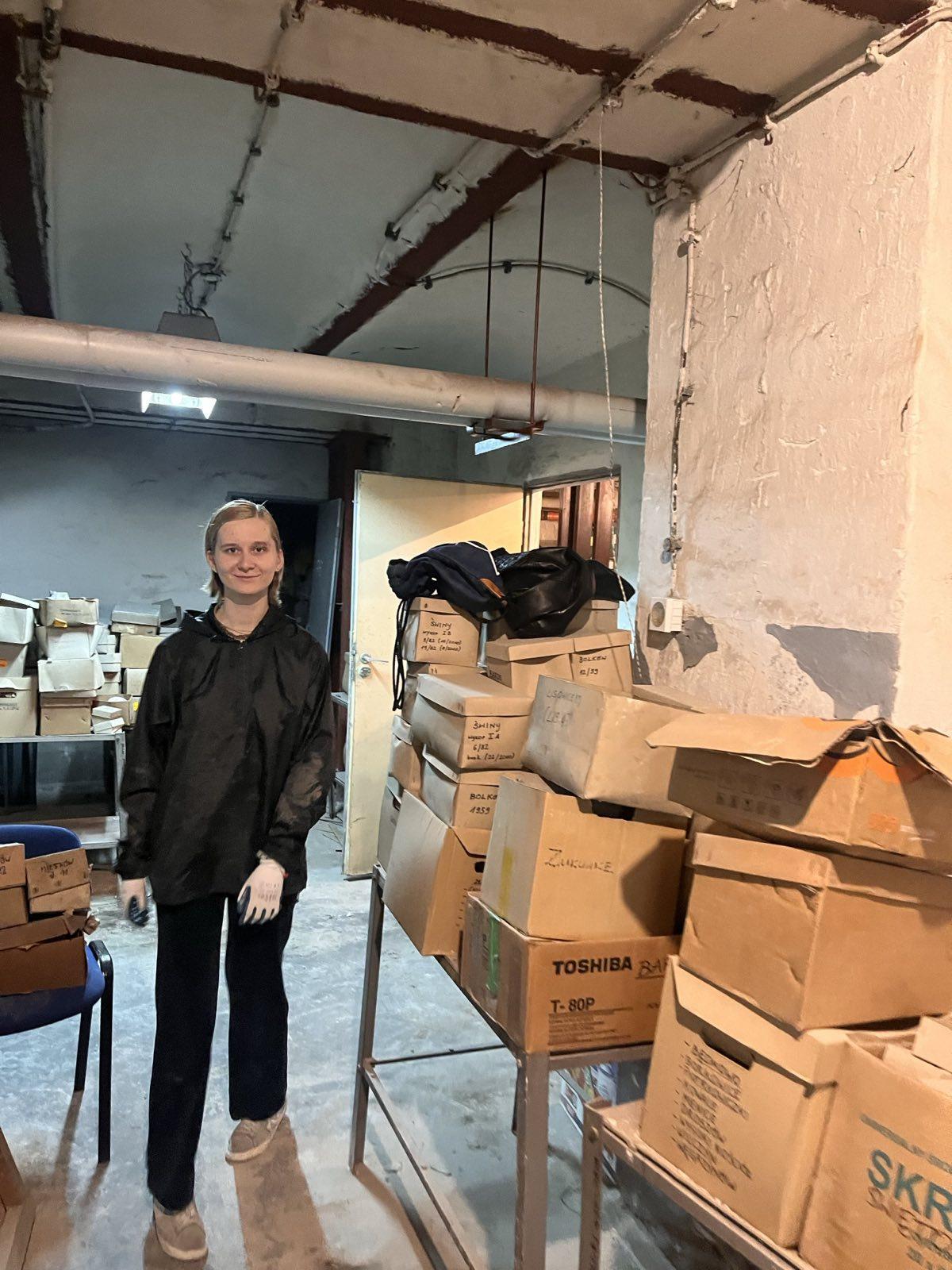 A Student in the Szewska cellar, near cardboard boxes