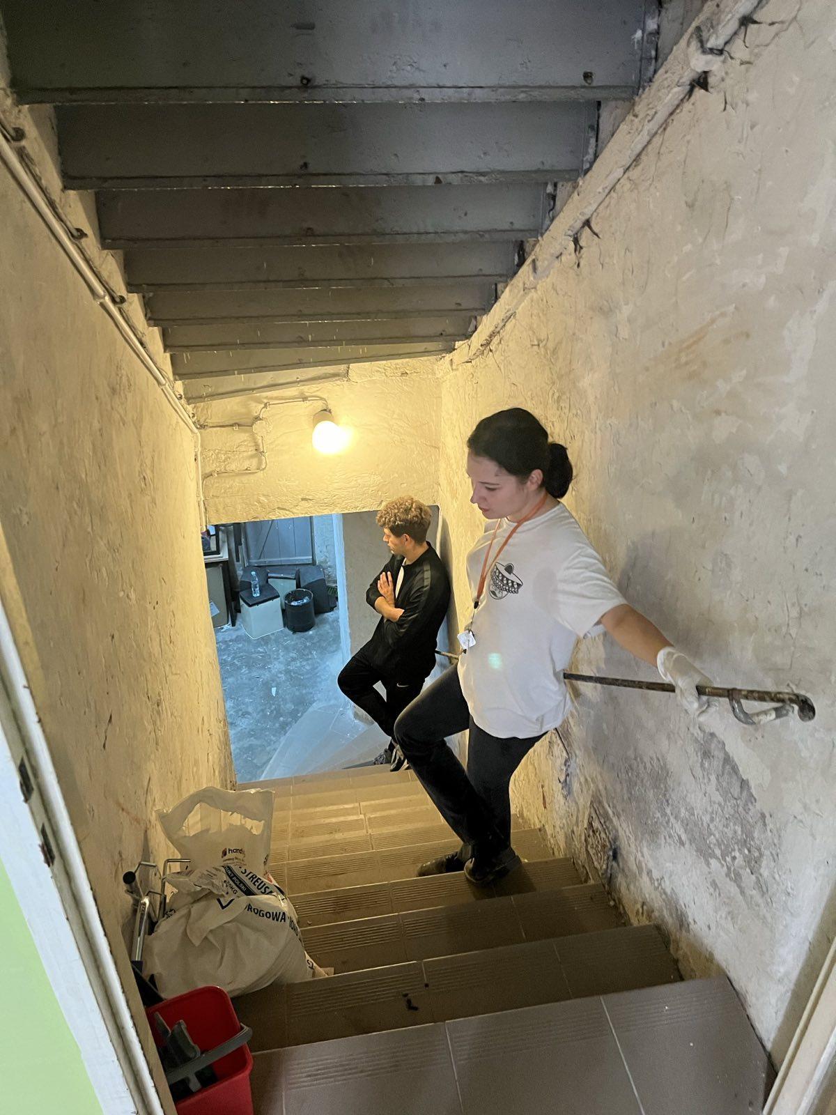 Two persons on the stairs down into the cellar.